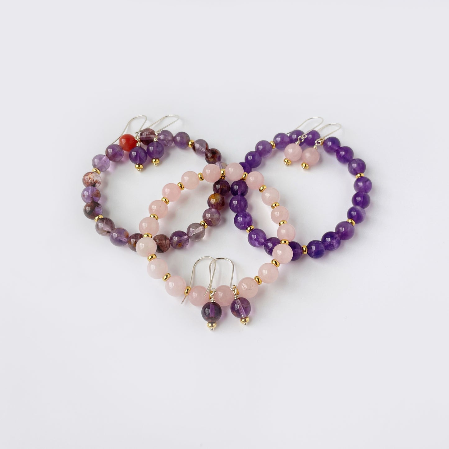 3 gemstone stretch bracelets laid out with their matching earrlings