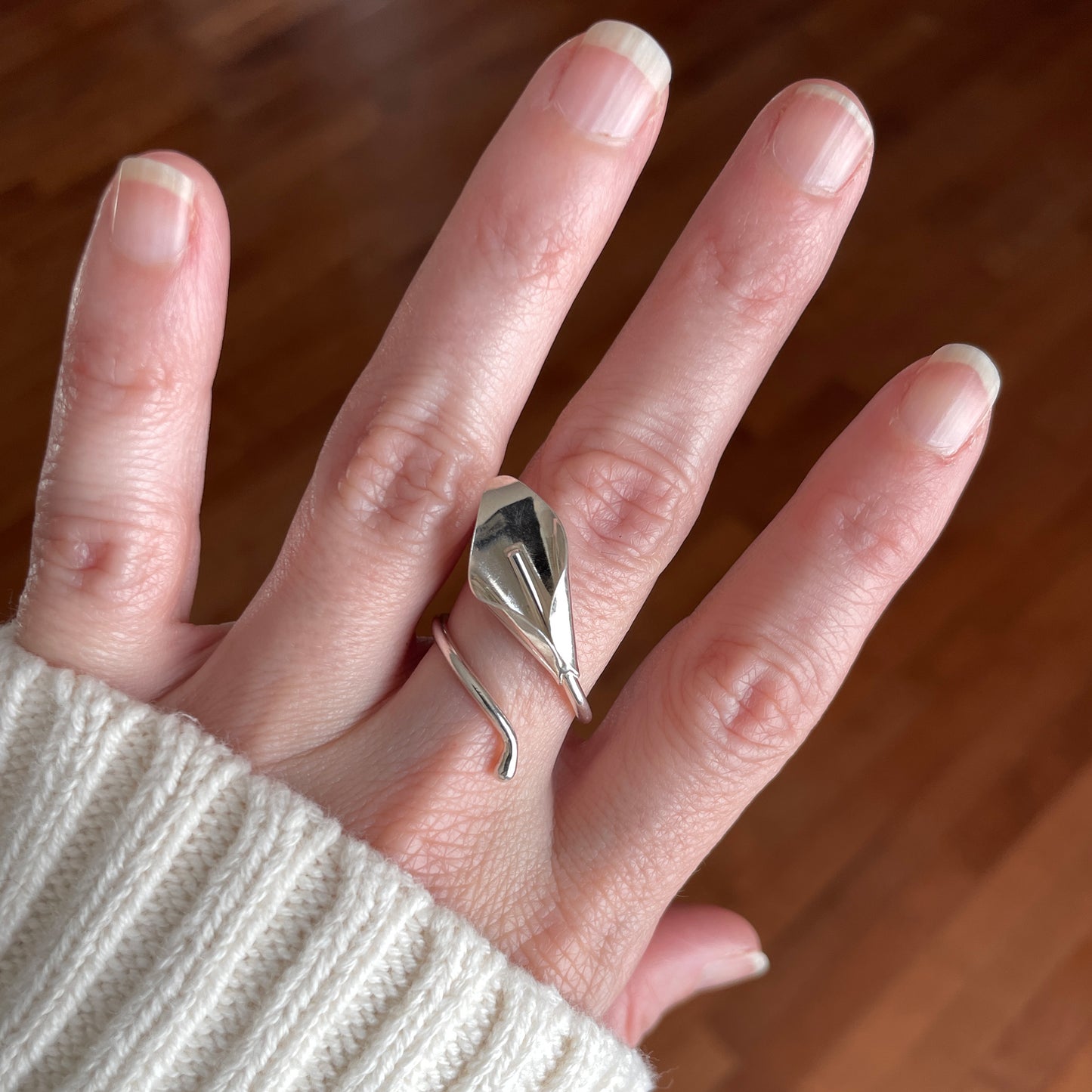 Hand wearing a silver ring with a lily design