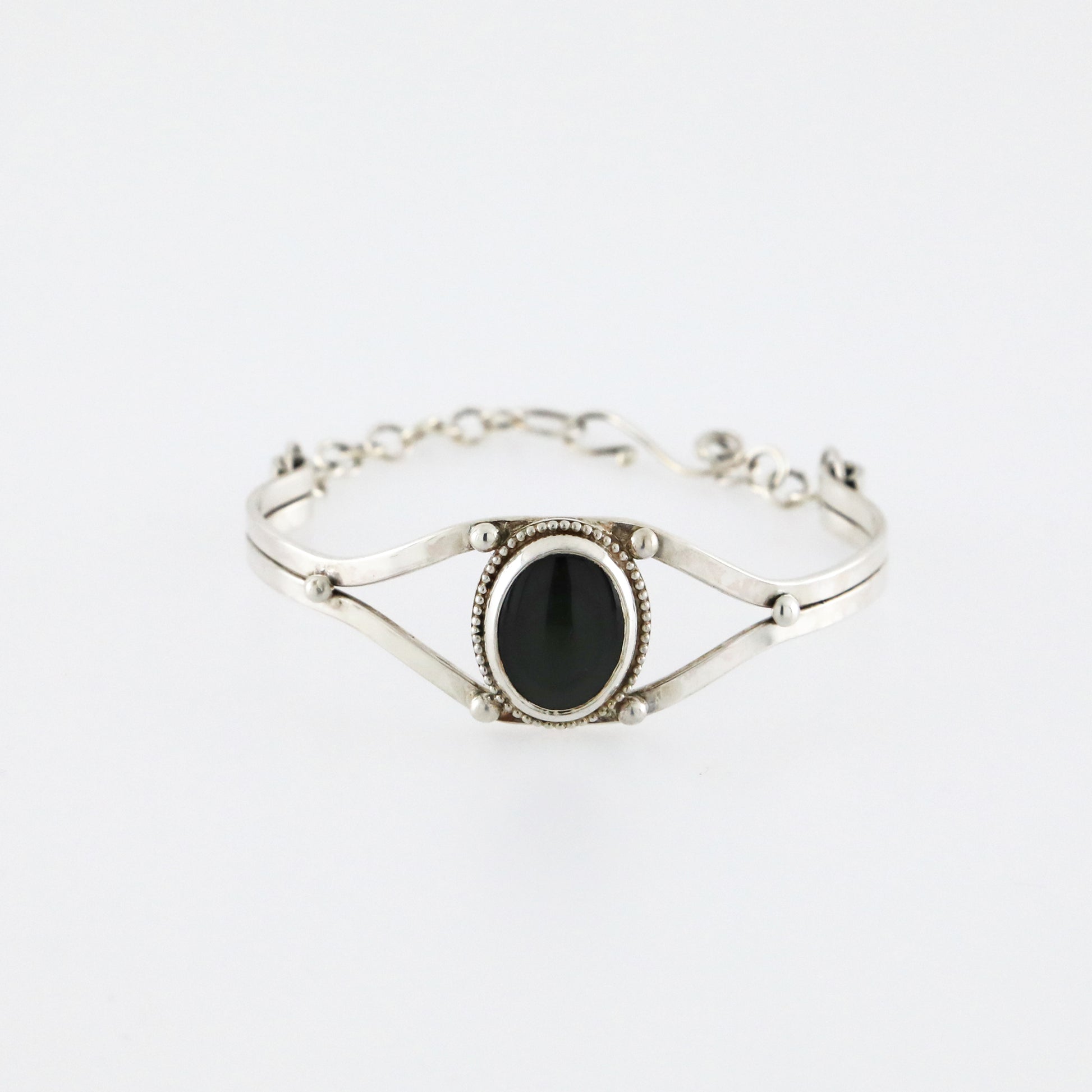 Silver cuff bracelet with a dark obsidian gemstone.