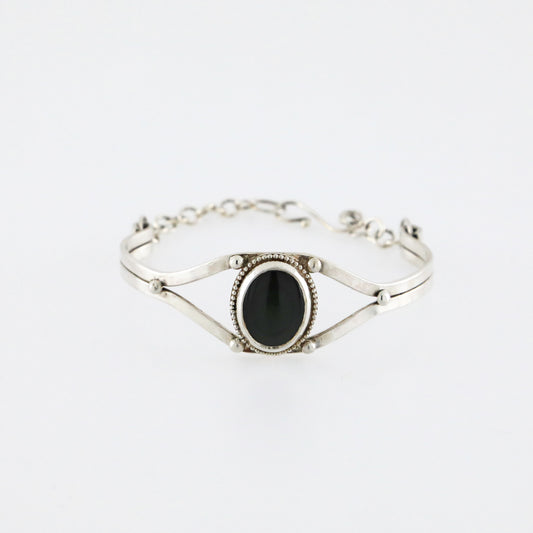 Silver cuff bracelet with a dark obsidian gemstone.