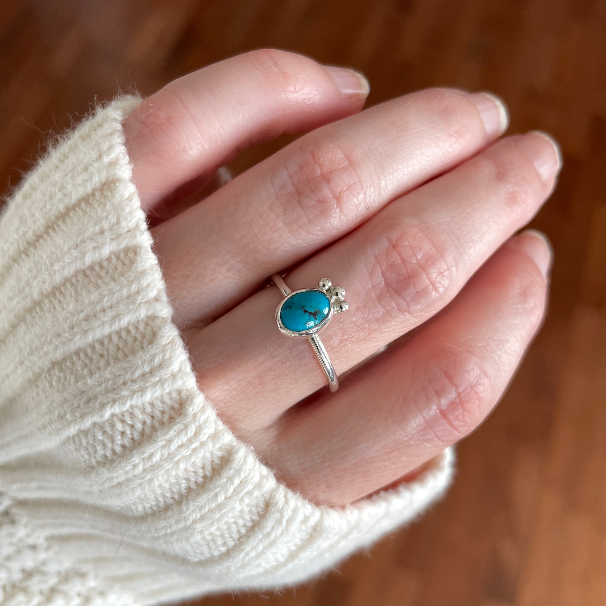 silver and turquoise ring worn on a hand