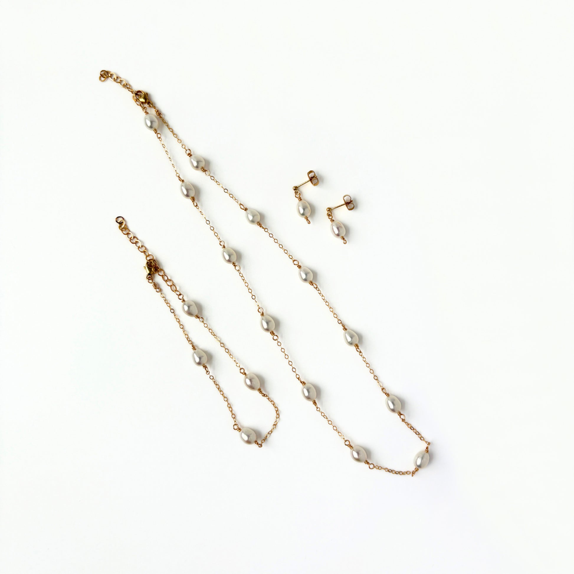 Pearl necklace, bracelet, and earrings set on a white background