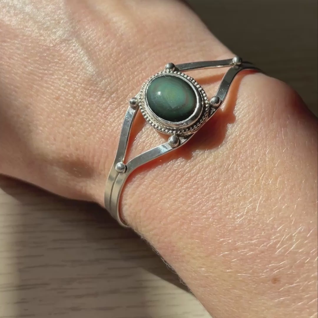 video to highlight the colors of therainbow obsidian center gemstone of this silver cuff bracelet.